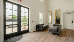 A hotel lobby with a large sliding glass door, a reception desk, a sofa, a mirror, and a door labeled 'FOUR'. - 5 Star Flat Downtown Trussville (Trussville)