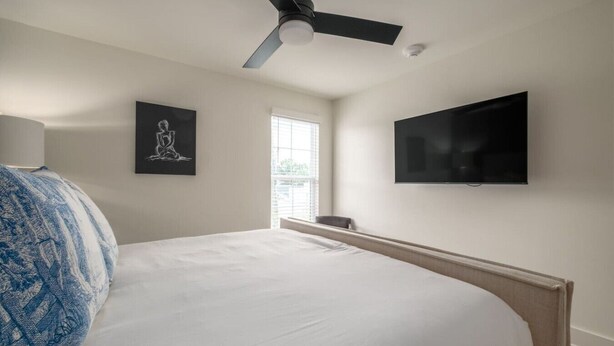 A bedroom with a bed, a ceiling fan, a TV, and a window. - 5 Star Flat Downtown Trussville (Trussville)