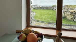 A bowl of fruit on a windowsill with a view of a grassy area and a stone wall. - Apartment 471 - Clifden - sleeps 4 guests  in 2 bedrooms (Clifden)