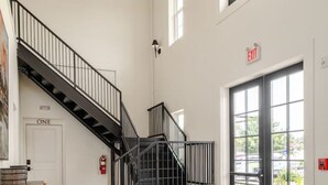 A spacious room with a staircase, a bed, and a table. - Luxury Penthouse in Entertainment District (Trussville)