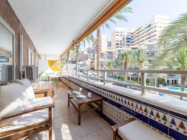 A balcony with a view of a cityscape, including palm trees and multi-story buildings.