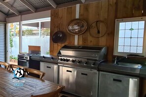 A kitchen with a stainless steel stove, oven, and sink, wooden panel walls, and a window with a view.