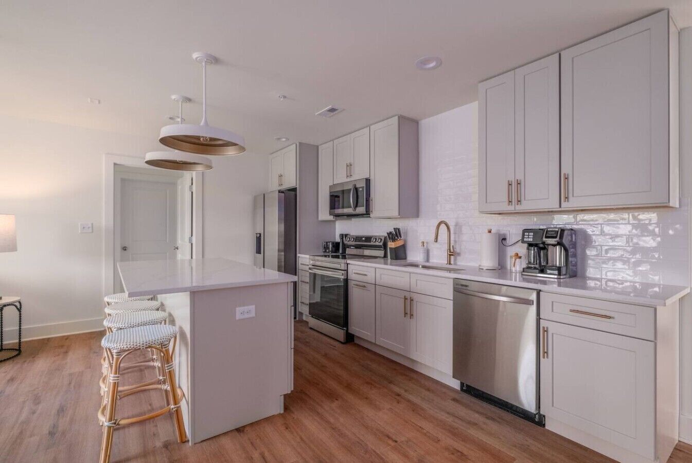 Una cocina moderna con armarios blancos, electrodomésticos de acero inoxidable y una isla central.