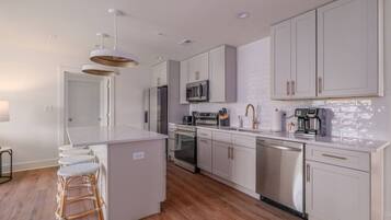 Una cocina moderna con armarios blancos, electrodomésticos de acero inoxidable y una isla central.