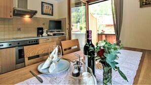 A kitchen with a dining table set for two, a wine bottle, and a vase with flowers. - Paradiso by Interhome (Ramsau im Zillertal)