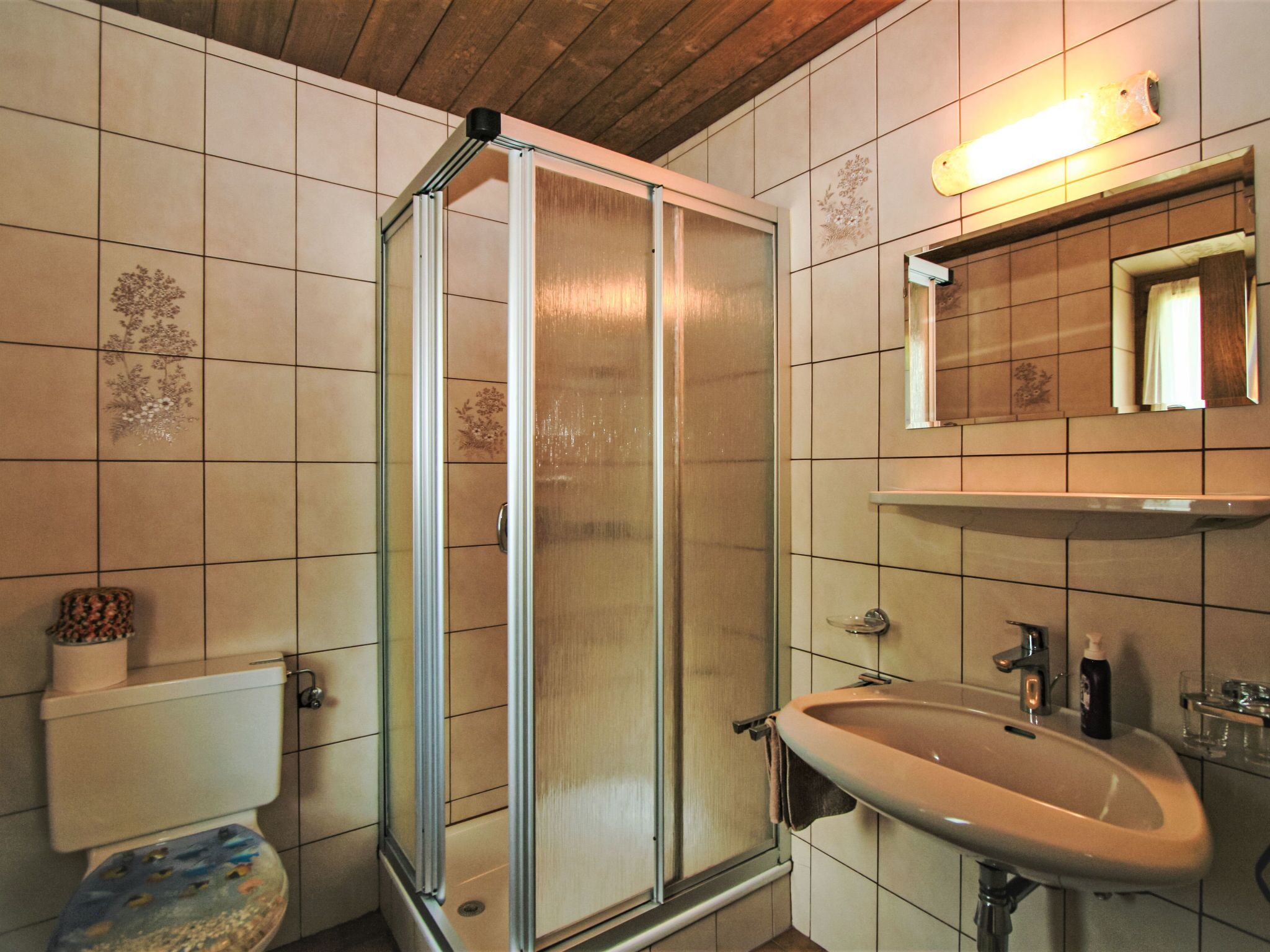 Ein Badezimmer mit Dusche, Toilette, Waschbecken und Spiegel.