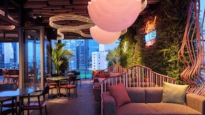 A modern lounge area with seating, a view of the cityscape, and decorative lighting. - Kin Hotel Thi Sach (Ho Chi Minh City)