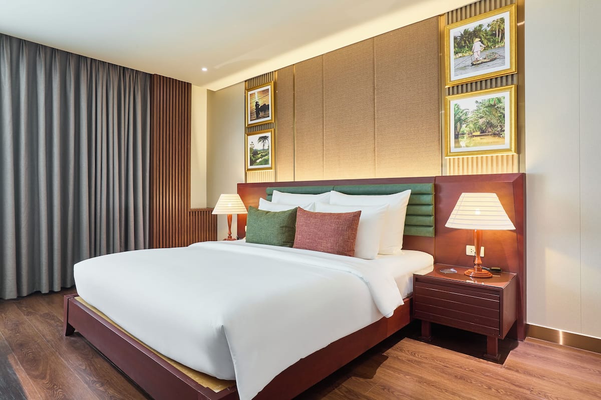 Ein Hotelzimmer mit einem großen Bett, zwei Nachttischen mit Lampen, einem Holzkopfschild und gerahmten Bildern an der Wand.