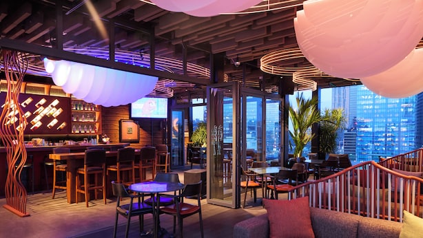 A modern bar area with a city view, wooden furniture, and ambient lighting. - Kin Hotel Thi Sach (Ho Chi Minh City)
