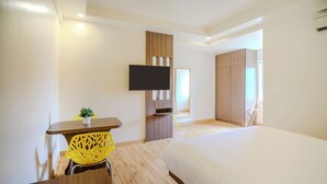 A modern hotel room with a large bed, a desk with a chair, a television mounted on the wall, and a wardrobe. - Bloom Hotel - HAL Old Airport Rd (Bengaluru)