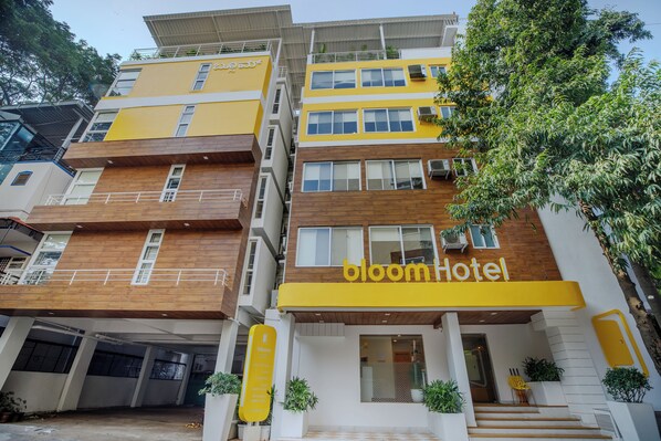 A multi-story hotel with a yellow facade, multiple balconies, and a sign reading "bloom hotel". - Bloom Hotel - HAL Old Airport Rd (Bengaluru)