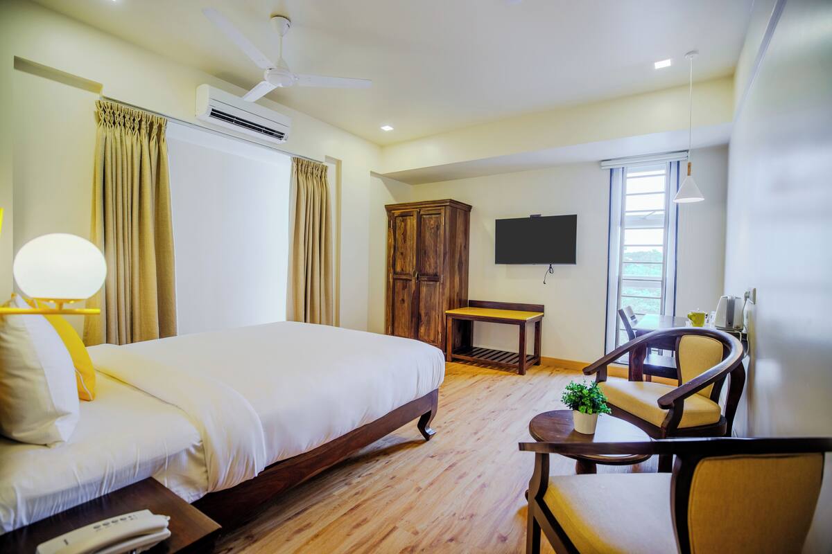Une chambre d’hôtel comprenant un lit, une armoire en bois, un téléviseur, une table et une chaise.