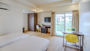 A hotel room with a bed, a desk, a chair, a TV, and a window with curtains. - Bloom Hotel - HAL Old Airport Rd (Bengaluru)