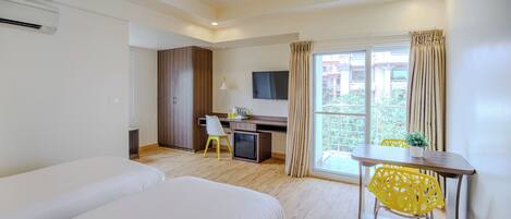 A hotel room with a bed, a desk, a chair, a TV, and a window with curtains.