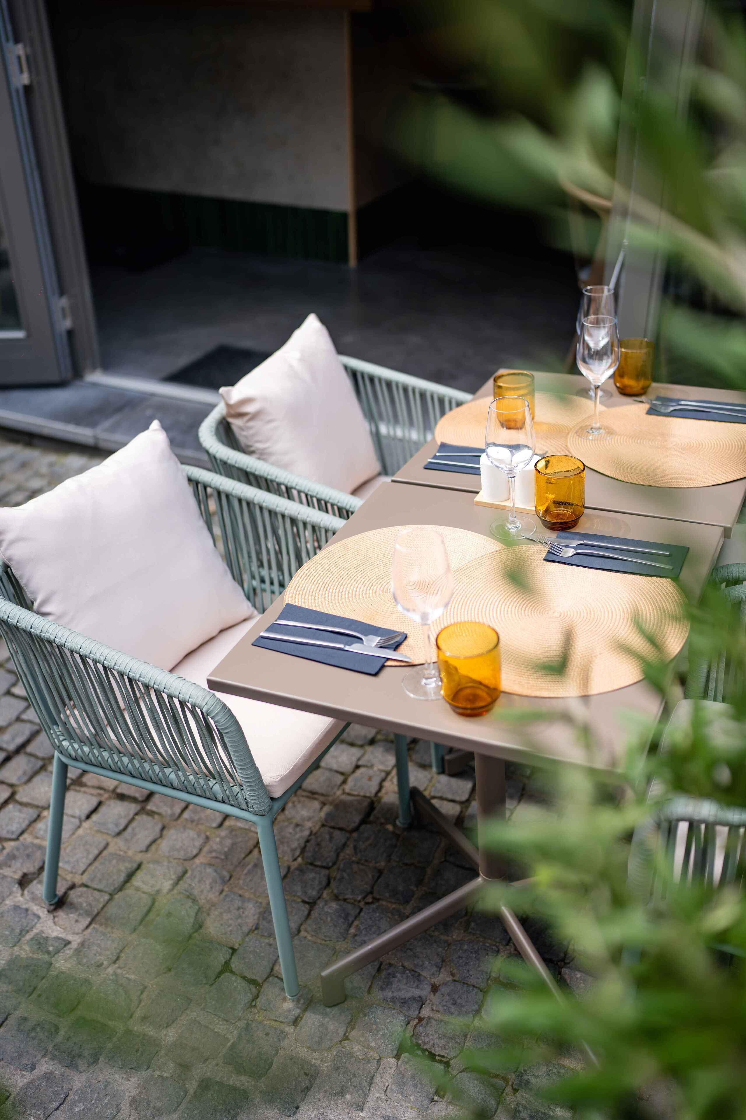 An outdoor dining area with wicker chairs and a table set for two.