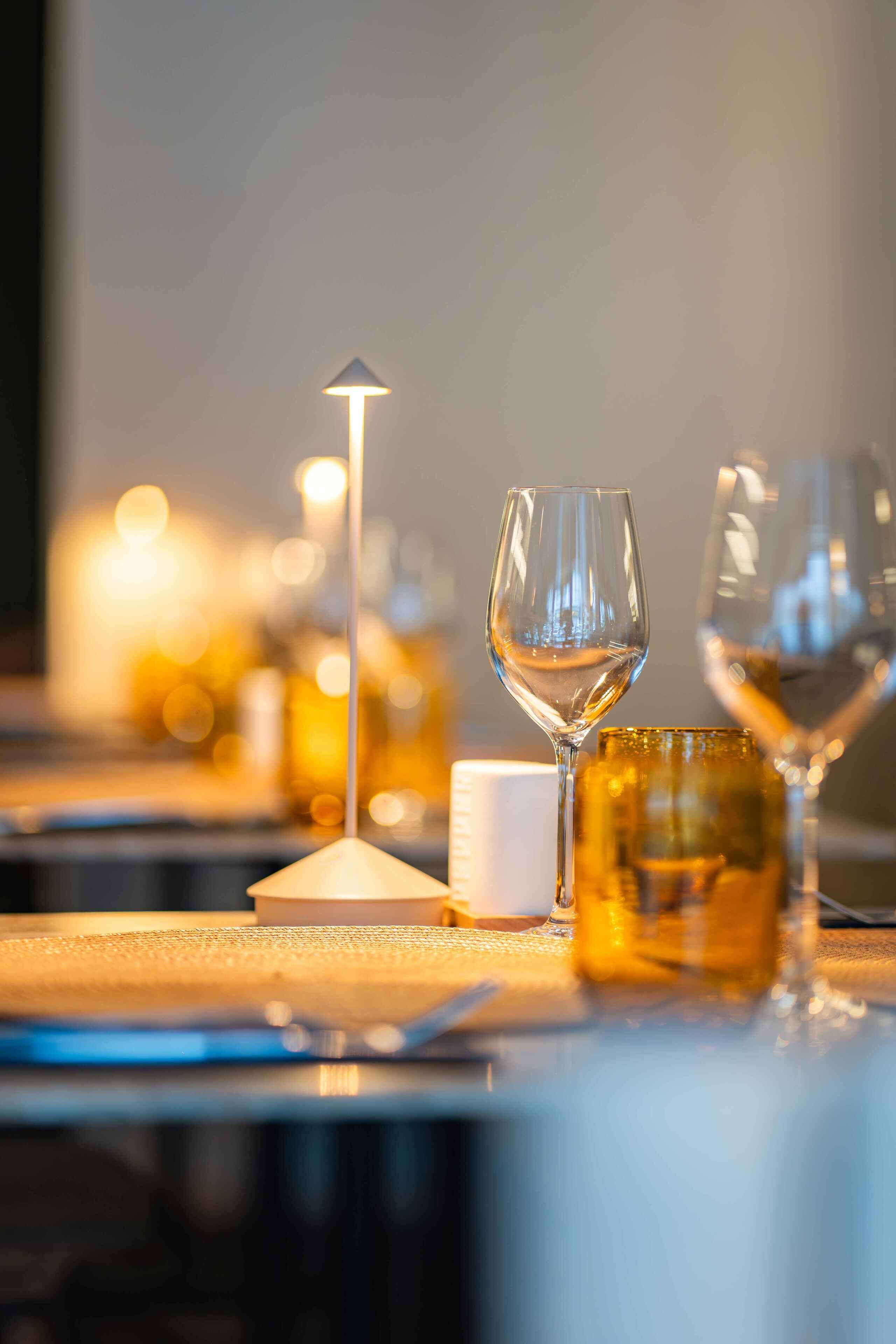 Uma mesa de jantar com uma vela, um copo de água e uma taça de vinho.