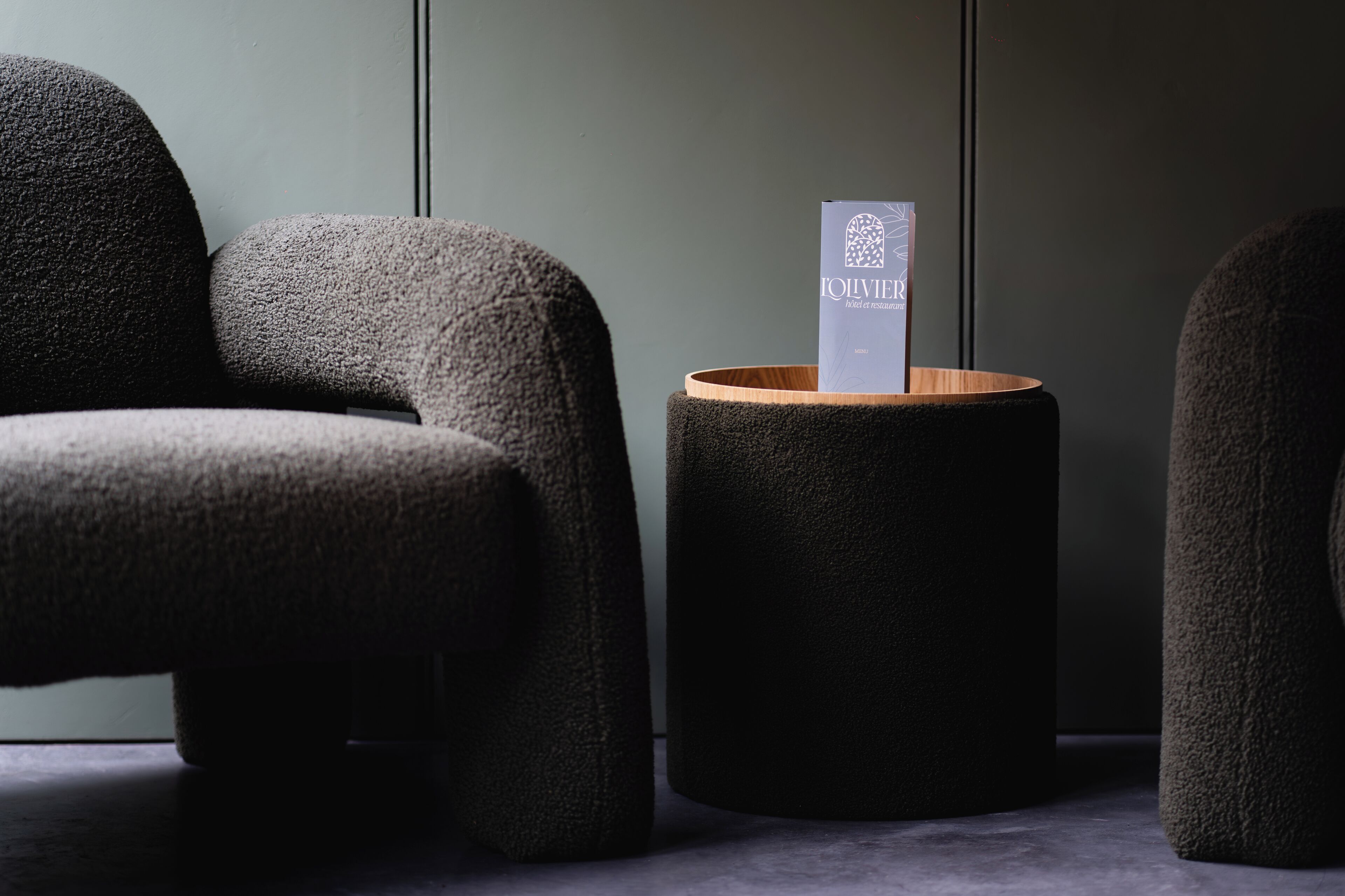 Une pièce moderne et minimaliste, avec un canapé sombre à la texture marquée et une petite table d’appoint en bois.