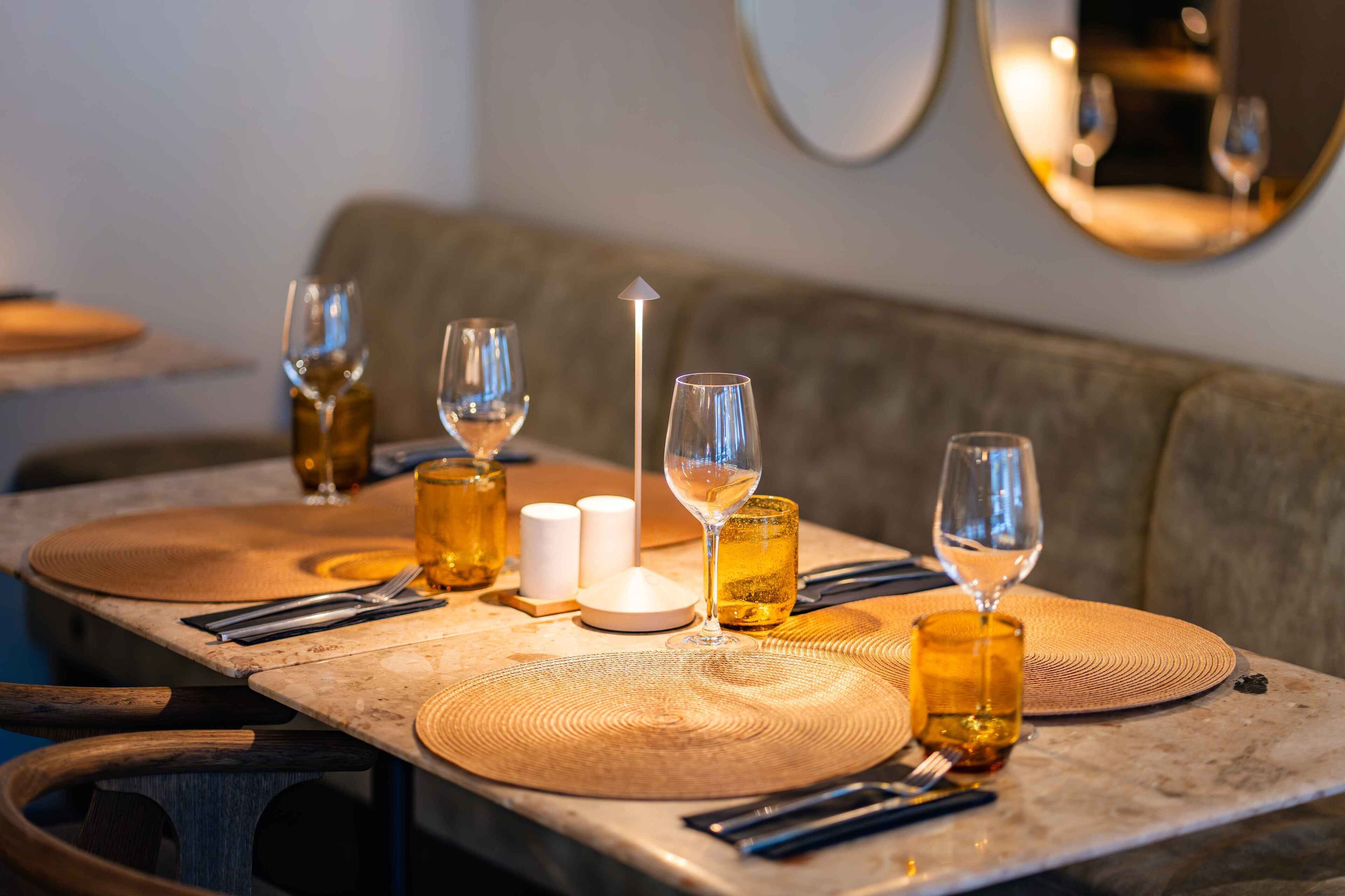 A dining table set with wine glasses, a candle, and a bottle of wine.