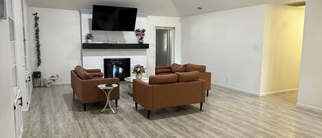 A spacious living area with a fireplace, two sofas, and a ceiling fan.