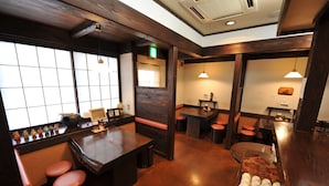 A restaurant interior with wooden tables, stools, and a counter with a tray of white cups. - HOTEL CROWNHILLS NARUTO (Naruto)