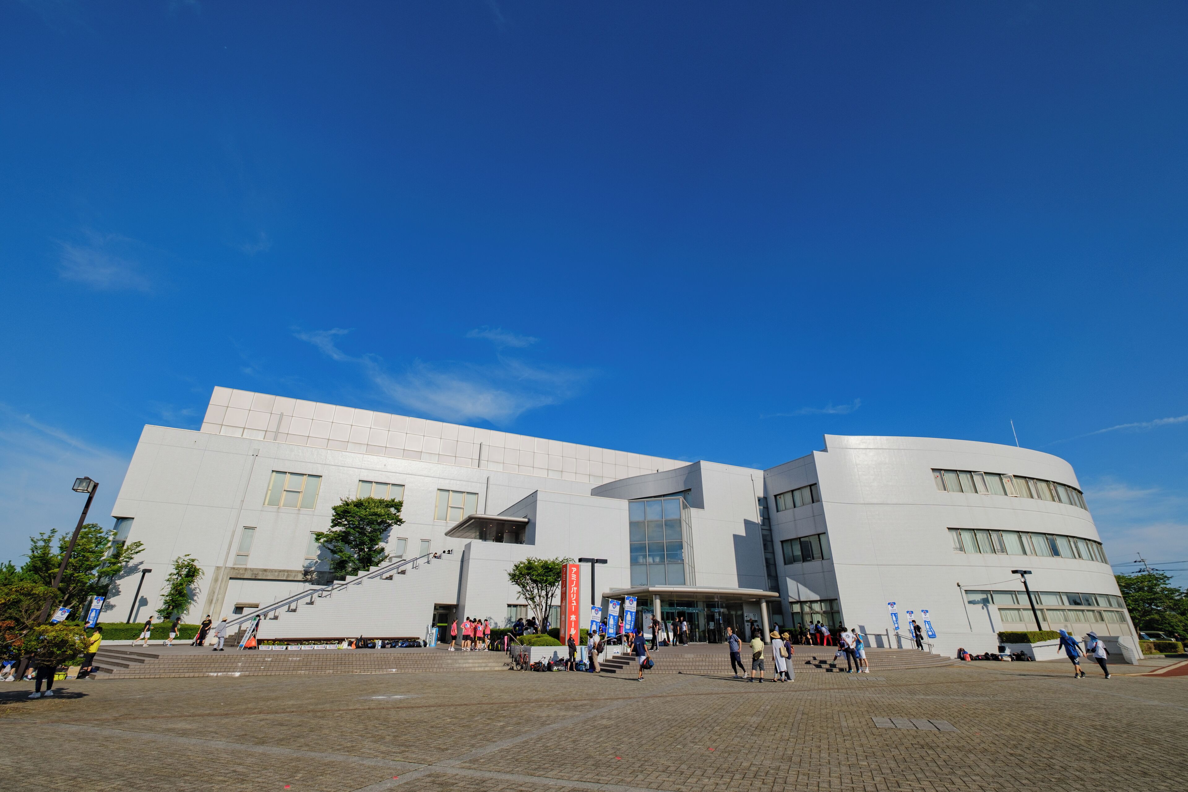 A modern building with a large entrance and steps leading up to it.