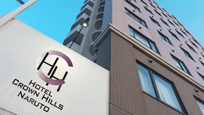 The exterior of Hotel Crown Hills Naruto, featuring a modern design with a prominent logo and a clear view of the building's facade. - HOTEL CROWNHILLS NARUTO (Naruto)
