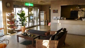 A lobby with a reception desk, seating area, and a plant. - HOTEL CROWNHILLS NARUTO (Naruto)