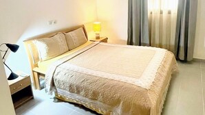 A bedroom with a bed, bedside lamp, and a window with curtains.