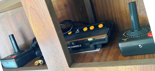 Un meuble en bois contenant un appareil électronique noir, un joystick jaune et un bouton rouge.