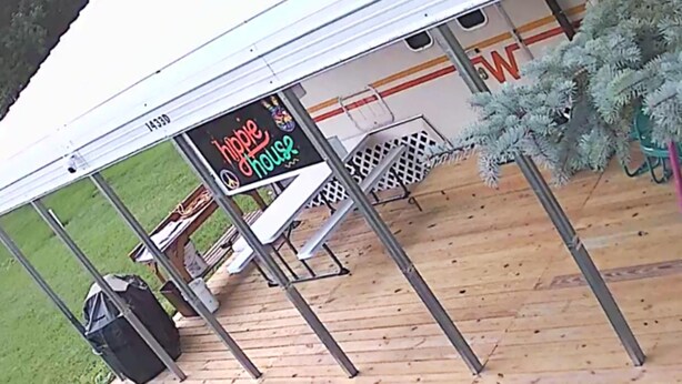 Een overdekt buitengebied met een bord waarop staat 'hippie house'.