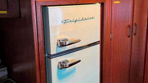 Een retro koelkast met vriesvak, ingebouwd in een houten kast met een ingebouwde verwarming erboven.