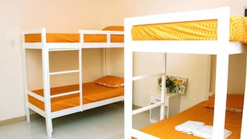 Habitación con literas, ropa de cama naranja y una pequeña mesa blanca con un cuadro.