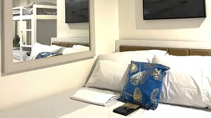 Hotellihuone, jossa on sänky, suuri peili ja taulu seinällä.