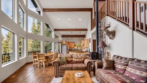A spacious living room with a wooden coffee table, leather sofas, and a fireplace. - A-Frame for 16 with Hot Tub & Sauna (Cle Elum)