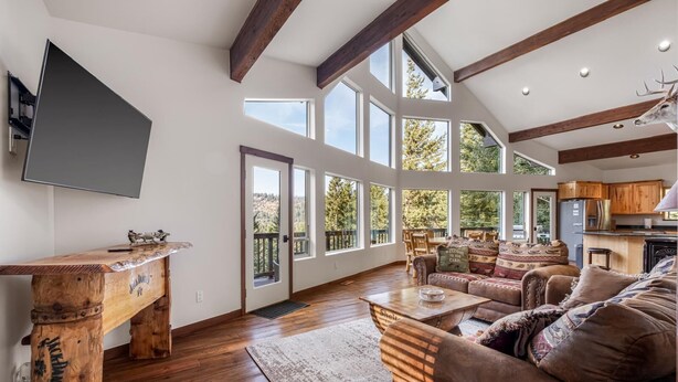 A spacious living room with a wooden coffee table, a sofa, and a television mounted on the wall. - A-Frame for 16 with Hot Tub & Sauna (Cle Elum)