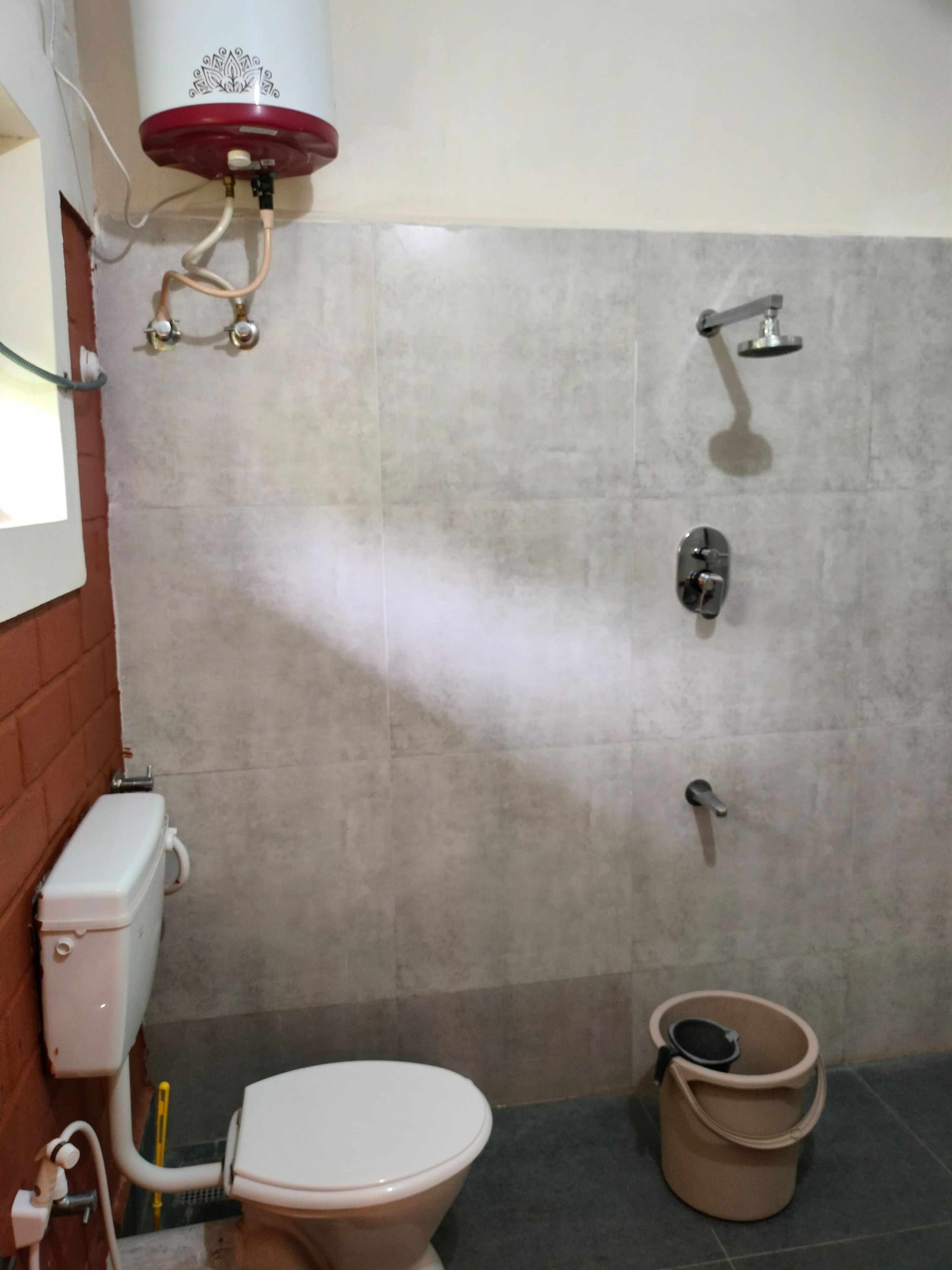 A bathroom with a toilet, a shower, and a bucket.
