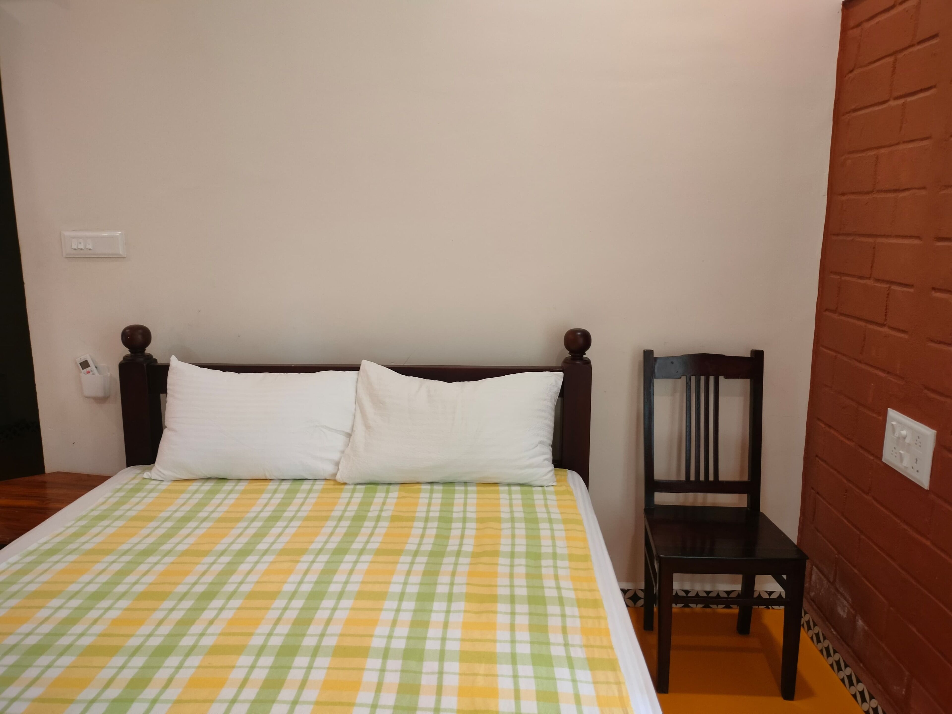 A bed with a checkered bedspread, a wooden headboard, and two white pillows.