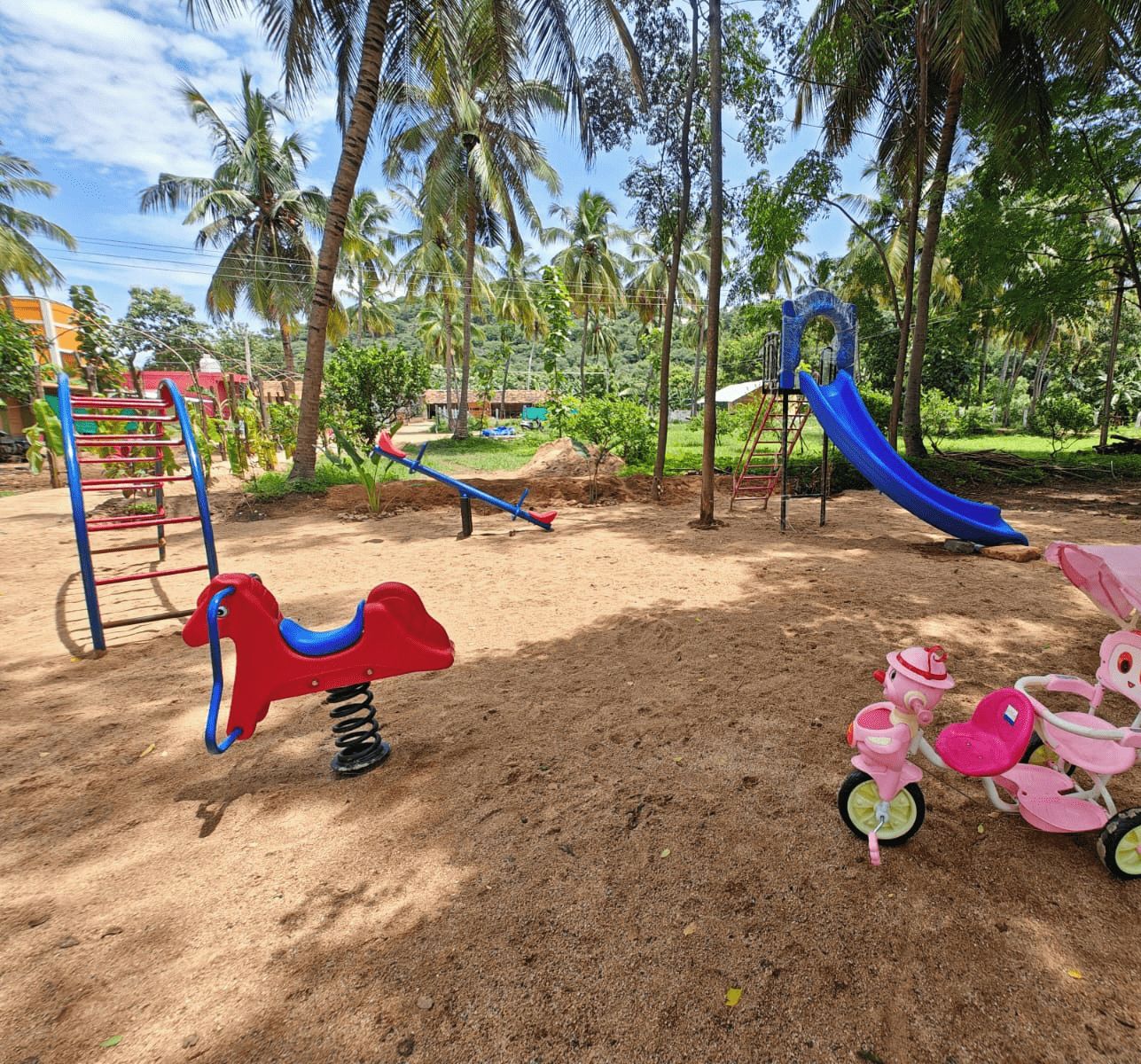 A playground with a slide, swings, and a seesaw.
