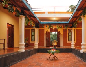 A spacious courtyard with a central fountain, surrounded by columns and a tiled floor. - TRK Farms Vinmeen Retreat (Katpadi)