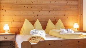 A wooden-paneled room with a bed, two bedside tables, and two wall-mounted lamps.