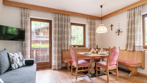 A cozy room with a wooden dining table, pink chairs, and a grey sofa.
