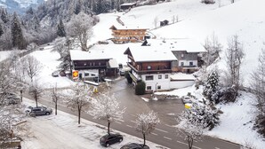 A snow-covered mountain village with traditional wooden buildings, a road, and parked cars.