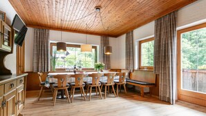 Un coin repas en bois avec une table et des chaises, un banc et un téléviseur posé sur un meuble.