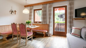 A cozy room with a wooden dining table, bench seating, a sofa, and a TV. - Beautiful apartments by the ski lift in Alpbach (Alpbach)