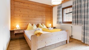 A wooden-paneled bedroom with a bed, bedside lamps, and a window with curtains.