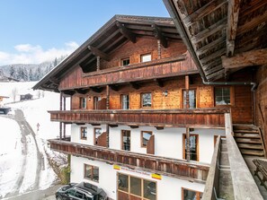 A multi-story wooden building with balconies, a sign indicating a business, and a snowy landscape in the background. - Two traditional apartments nearby ski lift (Alpbach)