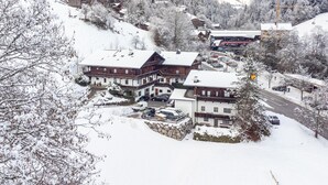 A snow-covered mountain village with traditional wooden buildings, a main road, and a parking area. - Right by the ski lift - 2 apartments in Alpbach (Alpbach)