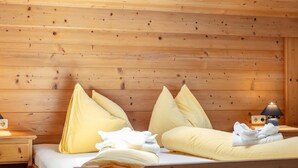 A wooden room with a bed, pillows, a nightstand, and a lamp. - Right by the ski lift - 2 apartments in Alpbach (Alpbach)