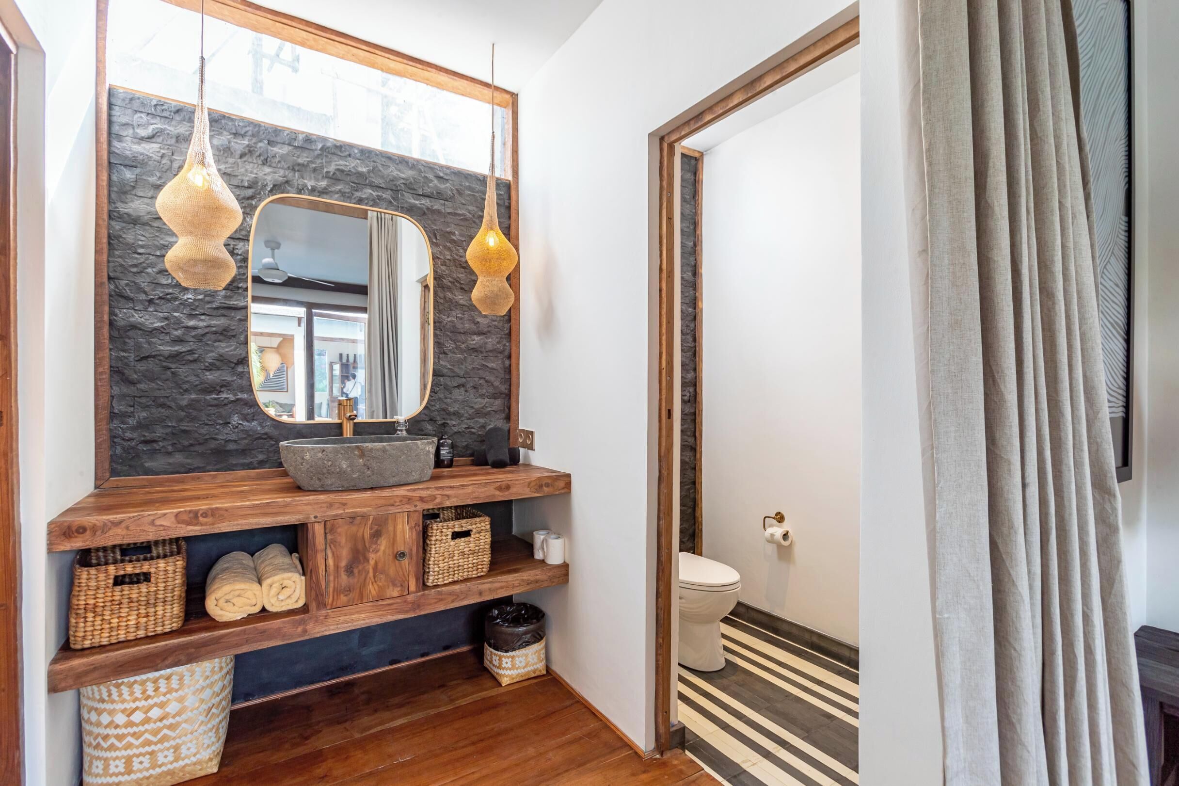 Une salle de bain avec un lavabo en pierre, un meuble-lavabo en bois et un miroir.