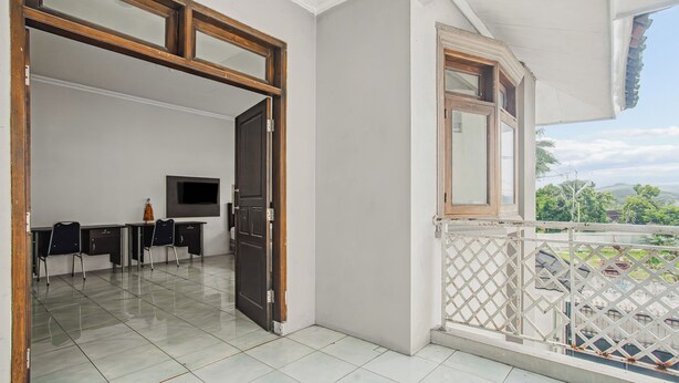 A spacious room with a balcony, a dining area with chairs and a table, and a TV mounted on the wall. - Collection O Bogor Near Ipb University Formerly Yasmin (Dramaga)